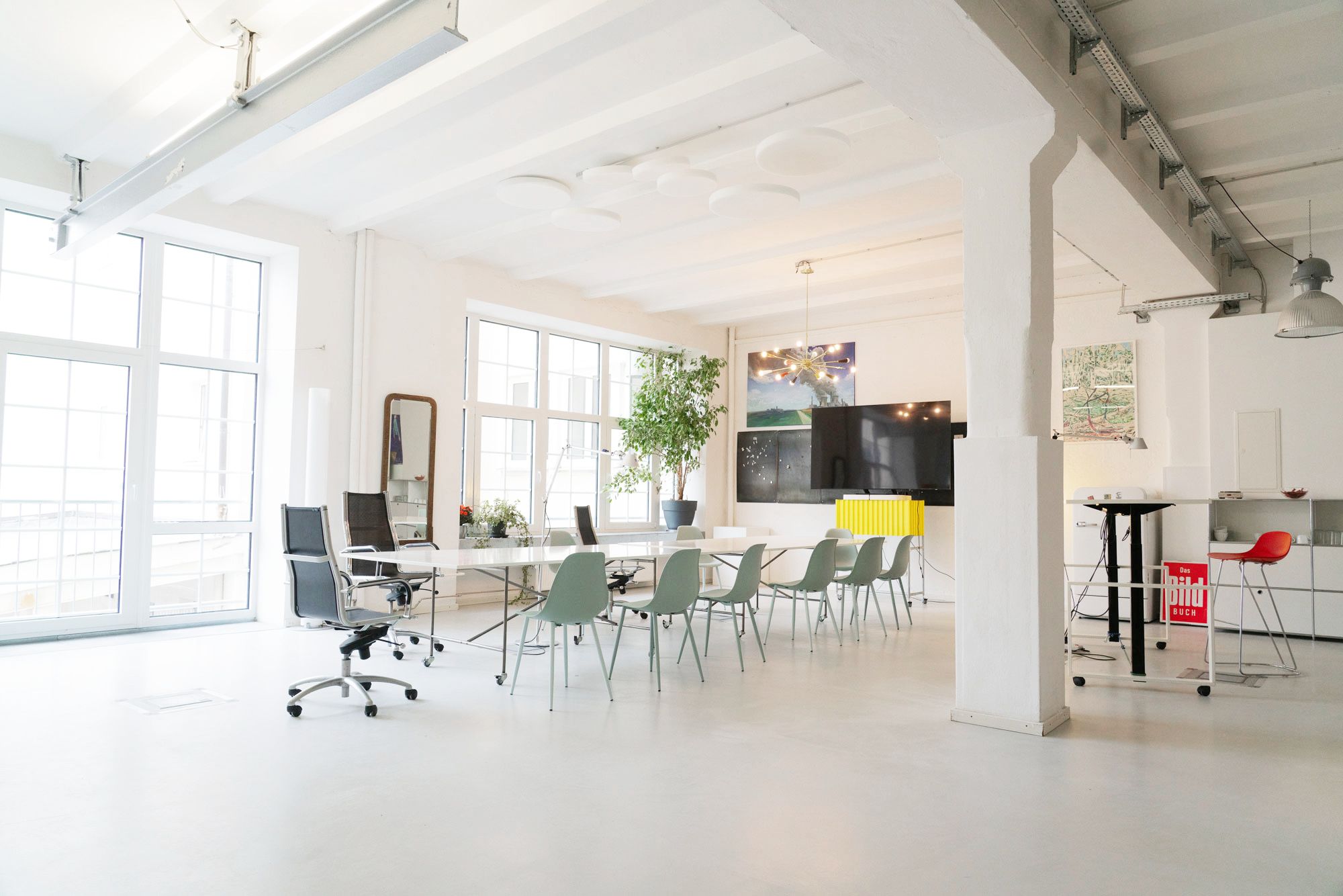 ein großer Raum / Loft mit einem großen Tisch und Stühlen und einer großen Fensterfront